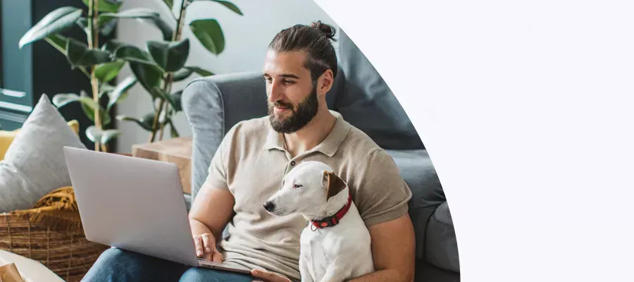 man sitting on the floor with dog looking at his laptop